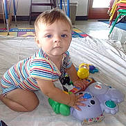 Jaxen joined the competition — help win amazing prizes! baby, child, toy, blanket, striped_clothing, floor, indoor, table, chair, window, door, colorful, play, kneeling, curious, person, floor_mat, plastic_toy, light, room
