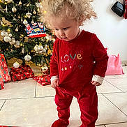 Alba a rejoint le concours — aidez-le/la à gagner de superbes lots ! toddler, child, curly_hair, red_clothing, christmas_tree, christmas_decorations, wrapped_gifts, holiday, indoor, tile_floor, gift_box, festive, cute, standing, curious, person, holiday_lights, home, winter, celebration