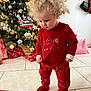 toddler, child, curly_hair, red_clothing, christmas_tree, christmas_decorations, wrapped_gifts, holiday, indoor, tile_floor, gift_box, festive, cute, standing, curious, person, holiday_lights, home, winter, celebration