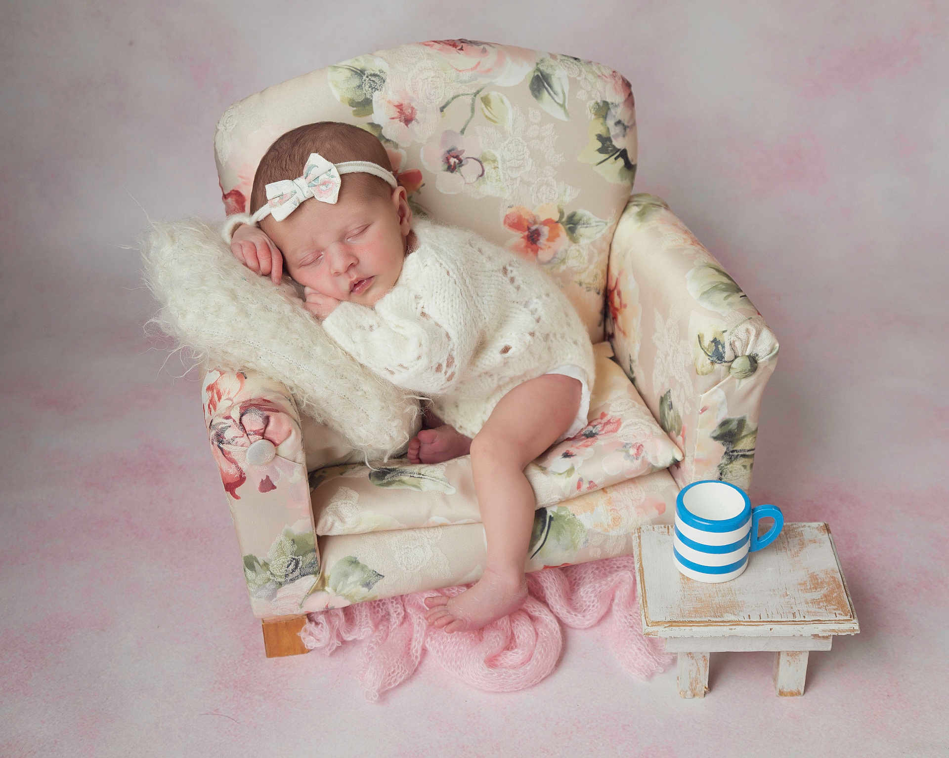 Mia joined the competition — help win amazing prizes! baby, sleeping, infant, knitwear, headband, bow, miniature_chair, floral_pattern, pillow, small_table, striped_cup, pink_background, cozy, cute, peaceful, indoor, portrait, newborn, soft_texture, resting