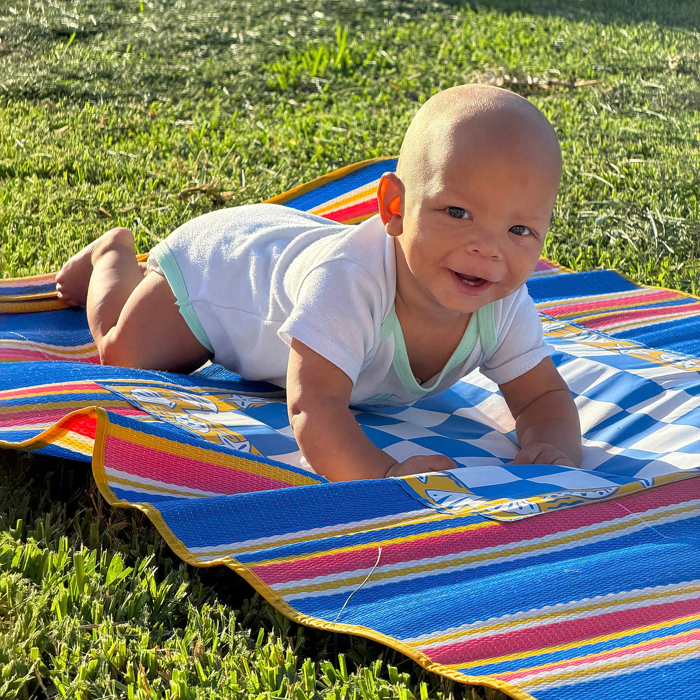 Zito joined the competition — help win amazing prizes! baby, child, grass, outdoor, sunlight, mat, crawling, smiling, onesie, happy, infant, person, playtime, colorful, striped_mat, nature, greenery, summer, cute, portrait