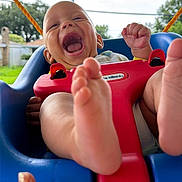 Zito is registered to the contest to win money with this photo: baby, child, swing, outdoor, happy, laughing, feet, hand, playful, blue, red, grass, sky, daylight, person, smile, backyard, toy, seat, fun