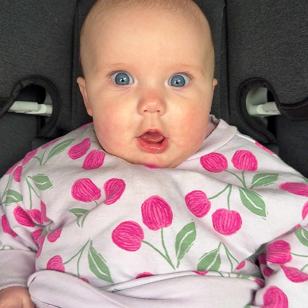 Isabella is registered to the contest to win money with this photo: apparel, baby, blue_eyes, car_seat, casual_wear, child, clothing, cute, expression, face, graco, indoors, infant, pattern, person, pink, portrait, sitting, striped_pants, young_child