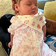 Ella joined the competition — help win amazing prizes! baby, sleeping, infant, floral_outfit, bib, tattoo, hand, couch, carpet, indoor, person, closeup, peaceful, cute, child, resting, soft, skin, newborn, comfort