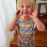 child, blonde_hair, striped_dress, rainbow_colors, smiling, playful, indoor, wooden_floor, curtain, furniture, person, happy, cute, portrait, toddler, hands, face, blue_eyes, casual_clothing, home
