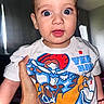 Aslan joined the competition — help win amazing prizes! baby, child, person, face, blue_eyes, tshirt, hand, indoor, curious_expression, young_child, cartoon_print, short_hair, skin, holding, portrait, cute, bright_eyes, smiling, infant, casual_clothing