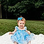 toddler, child, baby, blue_dress, bow, blanket, grass, outdoor, nature, smiling, sitting, curly_hair, cute, happy, portrait, greenery, daylight, young_child, innocence, playful