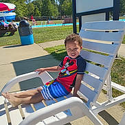 Ayden is registered to the contest to win money with this photo: boy, chair, child, concrete, daylight, grass, happy, leisure, mickey_mouse, outdoor, playful, poolside, recreation, relaxing, smile, summer, sunny, swimsuit, vacation, water