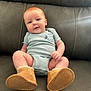 baby, infant, couch, blue_onesie, boots, footwear, smiling, cute, child, indoor, portrait, sitting, face, skin, head, happy, furniture, soft, warm, comfort