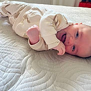 Marius participe au concours pour gagner de l'argent avec cette photo : baby, infant, smiling, tongue_out, lying_down, onesie, bunny_print, bed, quilt, texture, cute, child, happy, skin, face, hand, cozy, indoors, person, portrait