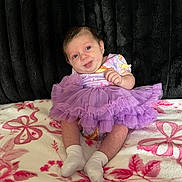Anluisa is registered to the contest to win money with this photo: baby, tutu, dress, purple, blanket, floral, socks, infant, cute, smile, sitting, child, portrait, indoors, fabric, texture, person, young, soft, background