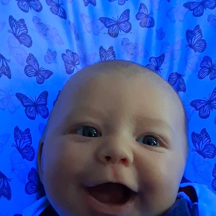 Kaiser joined the competition — help win amazing prizes! baby, smiling, face, blue, blanket, butterfly, pattern, infant, happy, portrait, child, clothing, cute, lying_down, closeup, eyes, skin, expression, indoors, person