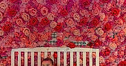 Semaj is registered to the contest to win money with this photo: baby, bench, casual_clothing, child, colorful, cozy, cute, floral_wall, flowers, happy, indoor, neon_light, neon_sign, pink, portrait, red, smiling, socks, wall_decor, white_bench