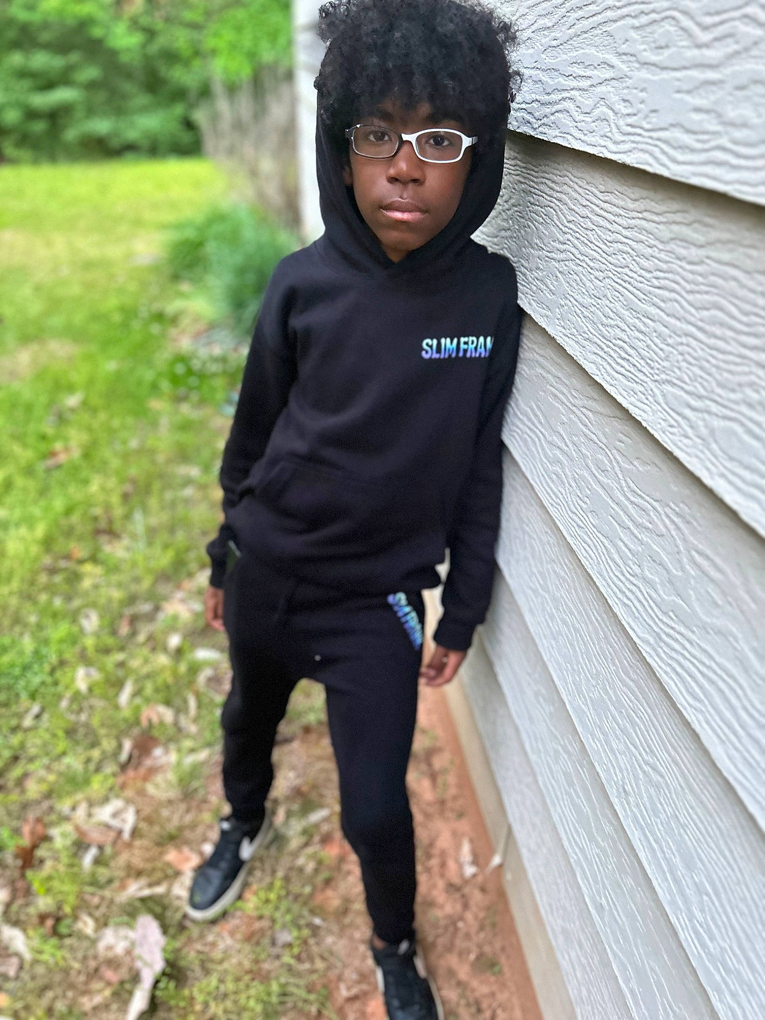 Carter is registered to the contest to win money with this photo: active_pants, cool, denim, electric_blue, eyewear, face, fashion_accessory, fun, grass, hoodie, knee, person, personal_protective_equipment, plant, sleeve, soil, sportswear, sweatpant, t_shirt, top