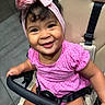 baby, child, smiling, happy, portrait, stroller, pink_bow, headband, pink_shirt, polka_dots, sitting, safety_harness, baby_carriage, face, eyes, hair, indoor, close_up, photography, adorable