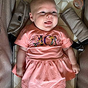Ava is registered to the contest to win money with this photo: baby, infant, child, smiling, dress, peach, pacifier, seat, cushion, comfort, tongue_out, cute, happy, clothing, person, indoor, closeup, skin, face, babywear