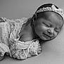 newborn, baby, sleeping, smiling, headband, ruffled_clothing, black_and_white, soft_texture, portrait, closeup, infant, peaceful, cute, resting, child, delicate, adorable, young, face, toddler