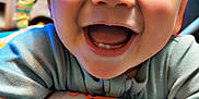Colton joined the competition — help win amazing prizes! baby, smiling, close_up, happy, child, infant, face, blue_clothing, toys, colorful, cute, cheerful, indoors, young_child, portrait, baby_seat, hands, expression, playful, joy