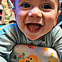baby, smiling, close_up, happy, child, infant, face, blue_clothing, toys, colorful, cute, cheerful, indoors, young_child, portrait, baby_seat, hands, expression, playful, joy