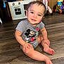 toddler, child, smiling, sitting, floor, wooden_floor, onesie, mickey_mouse, toy, play_kitchen, indoor, baby, cute, happy, person, clothing, face, hand, foot, home