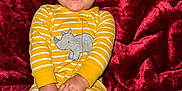 Colton is registered to the contest to win money with this photo: baby, child, smiling, yellow_onesie, rhino_patch, striped_clothing, red_blanket, happy, infant, cute, playful, lying_down, hands, feet, indoors, portrait, person, closeup, joy, soft_texture