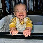 Colton joined the competition — help win amazing prizes! baby, child, smile, happy, playpen, clothing, indoor, person, hands, face, closet, furniture, yellow, white, long_sleeve, cute, infant, portrait, babywear, home