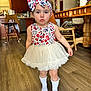 toddler, child, dress, headband, bow, socks, indoor, kitchen, wood_floor, wooden_chair, table, furniture, person, cute, expression, standing, floor, home, clothing, young_child