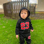 Aris joined the competition — help win amazing prizes! black_clothing, casual_wear, child, curly_hair, daylight, fence, grass, greenery, hoodie, innocent_expression, nature, number_23, outdoor, person, portrait, standing, toddler, urban_background, white_shoes, young_child