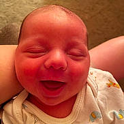 Kylo is registered to the contest to win money with this photo: baby, newborn, infant, smile, face, onesie, animal_print, happy, indoors, closeup, child, cute, sleepy, skin, person, head, expression, newborn_clothing, tiny, soft