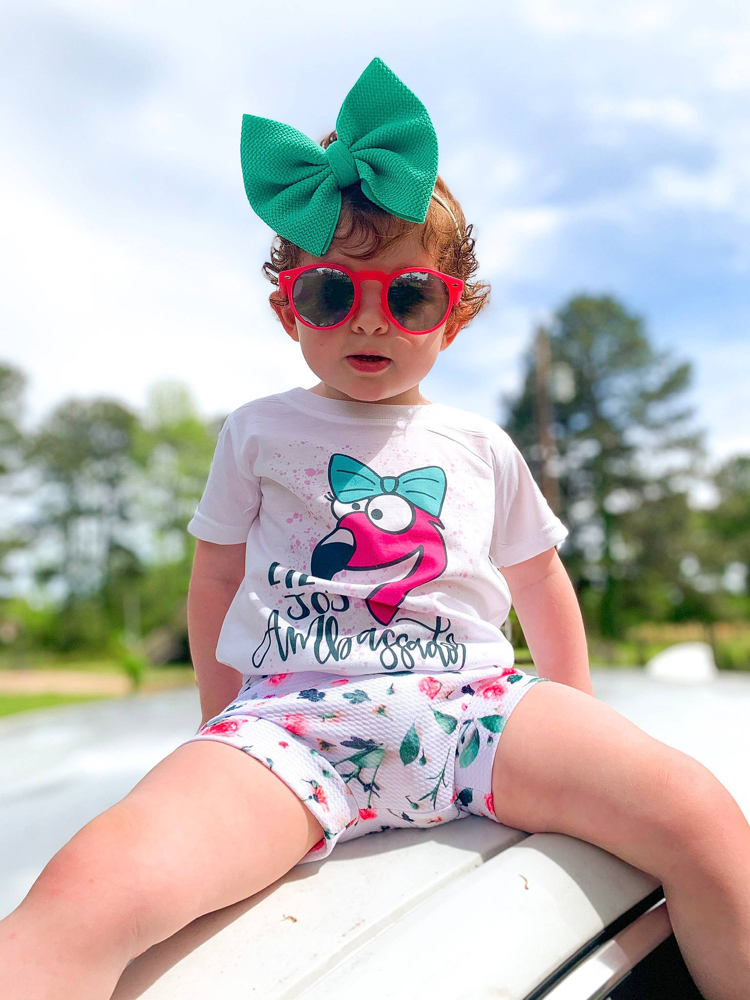 Adley is registered to the contest to win money with this photo: baby_toddler_clothing, blue, dress, eye, eyewear, glasses, goggles, grass, happy, human_body, leisure, person, pink, shorts, sky, sunglasses, t_shirt, thigh, toddler, vision_care