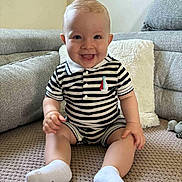 Marin participe au concours pour gagner de l'argent avec cette photo : baby, child, smiling, striped_clothing, socks, sitting, indoor, couch, pillow, blanket, happy, person, face, cute, infant, furniture, home, comfort, portrait, toddler