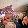 Jasper joined the competition — help win amazing prizes! baby, infant, toy, hand, blanket, clothing, person, indoor, furniture, colorful, chewing, cute, cozy, relaxed, couch, head, face, sleeve, child, young