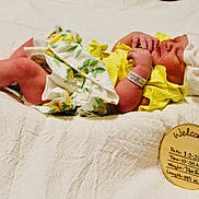 Daisy joined the competition — help win amazing prizes! baby, baby_girl, birth_details, blanket, closeup, cute, hospital_bracelet, indoors, infant, newborn, newborn_photography, peaceful, portrait, resting, sleeping, soft_texture, tender_moment, white_hat, wooden_sign, yellow_clothing