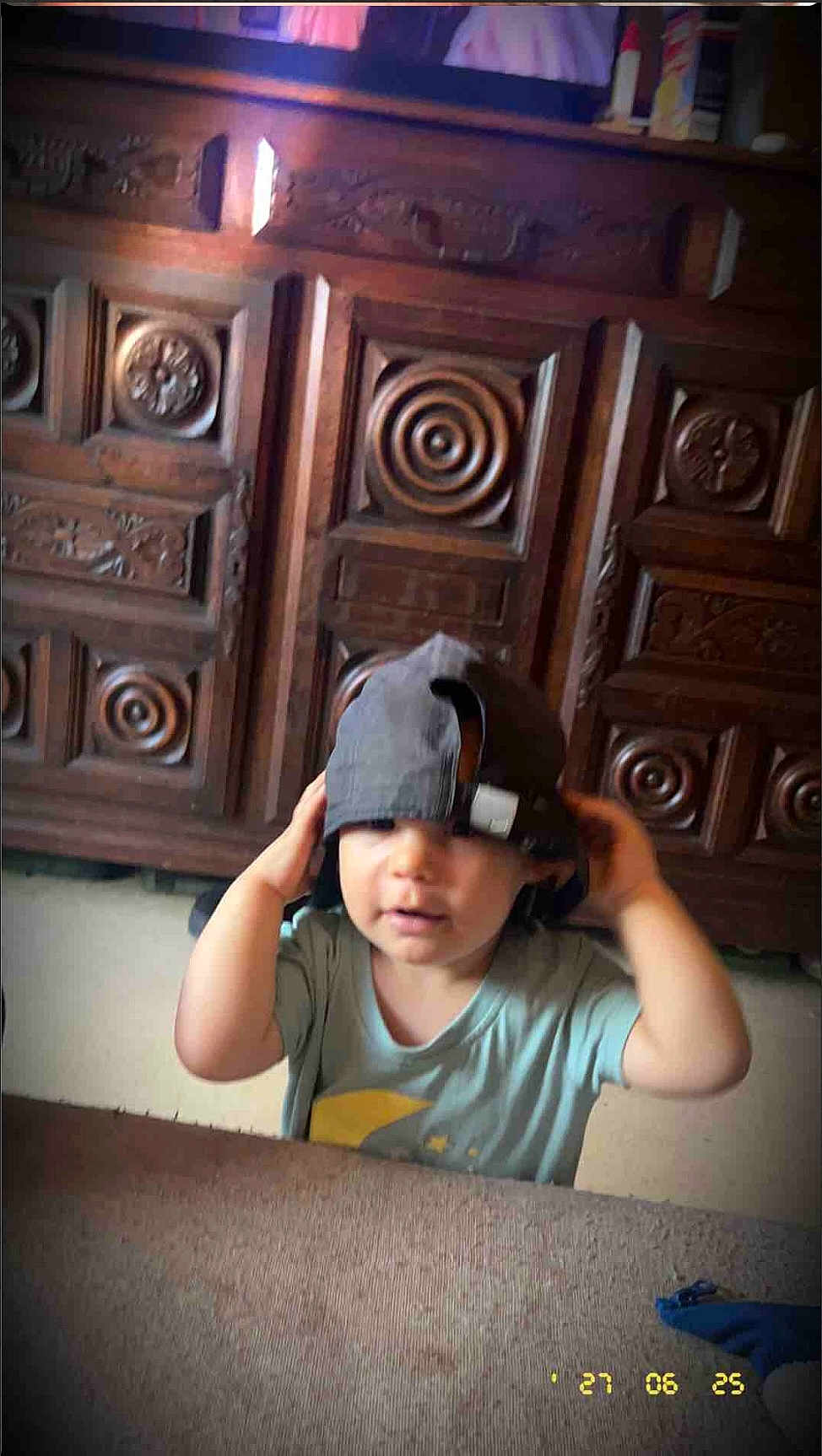 Louca participe au concours pour gagner de l'argent avec cette photo : toddler, child, cap, hat, indoor, carpet, wooden_cabinet, furniture, cute, baby, hands, clothing, portrait, face, headwear, person, room, playing, funny, expression
