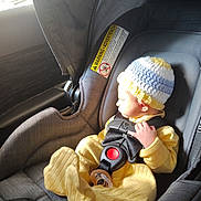 Marcus is registered to the contest to win money with this photo: baby, car_interior, car_seat, child, child_safety, crocheted_hat, cute, fabric, headwear, infant, interior, pacifier, resting, seatbelt, sitting, small_hand, soft_light, sunlight, window, yellow_clothing