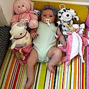 Millie is registered to the contest to win money with this photo: baby, infant, plush_toy, teddy_bear, stuffed_animal, pacifier, headband, striped_mat, colorful, child, cute, soft_toys, lying_down, indoors, pink, green_onesie, smiling, playtime, comfort, young