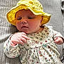 Millie joined the competition — help win amazing prizes! baby, yellow_hat, floral_dress, infant, hand, face, cushion, texture, pattern, closeup, portrait, cute, child, indoors, soft_lighting, expression, skin, sitting, young, person