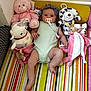 Millie joined the competition — help win amazing prizes! baby, infant, plush_toy, teddy_bear, stuffed_animal, pacifier, headband, striped_mat, colorful, child, cute, soft_toys, lying_down, indoors, pink, green_onesie, smiling, playtime, comfort, young