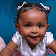 Aaliyah Love joined the competition — help win amazing prizes! blue_couch, bows, child, closeup, couch, curly_hair, eyes, face, food_package, hand, happy, indoor, person, pink_skirt, portrait, skin, smiling, table, toddler, white_clothing