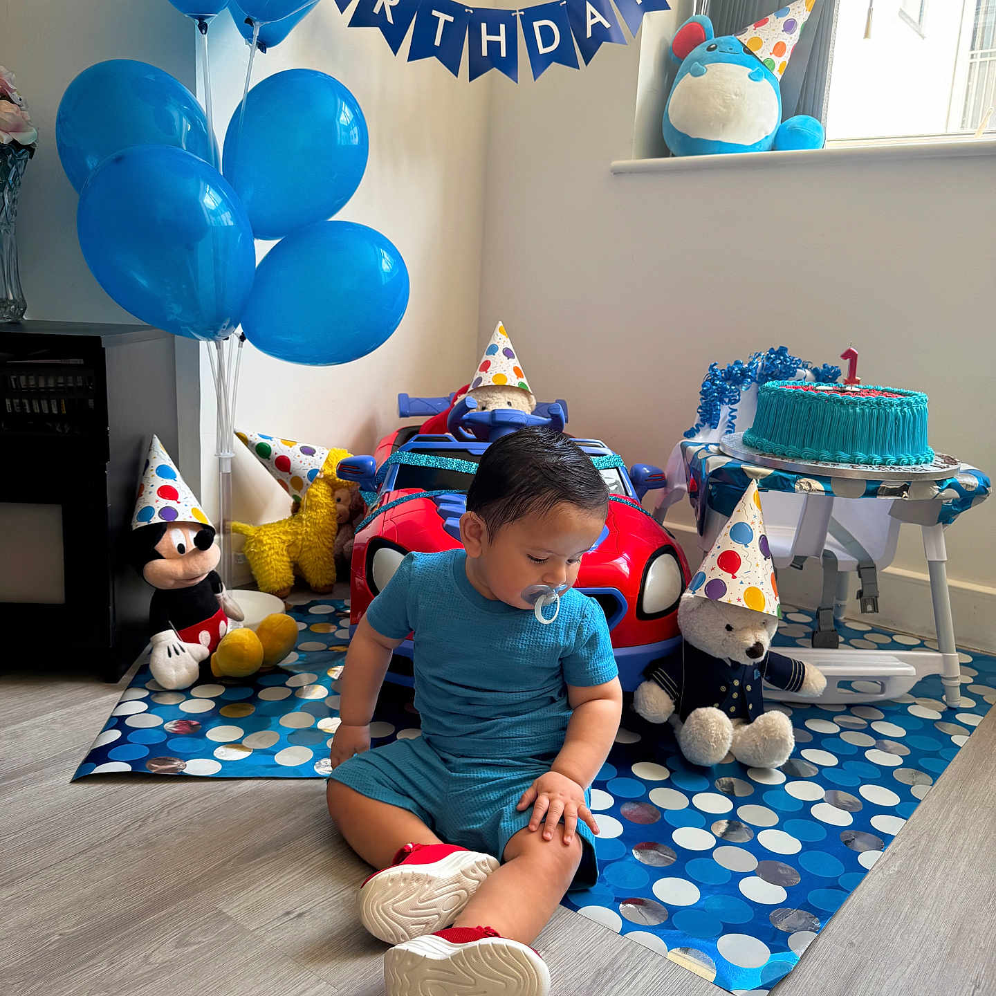 Huraira Muhammad joined the competition — help win amazing prizes! toddler, child, birthday, party_hat, balloons, cake, toy, stuffed_animal, blue, floor, mat, indoor, window, party, celebration, pacifier, clothing, sitting, decorations, toy_car