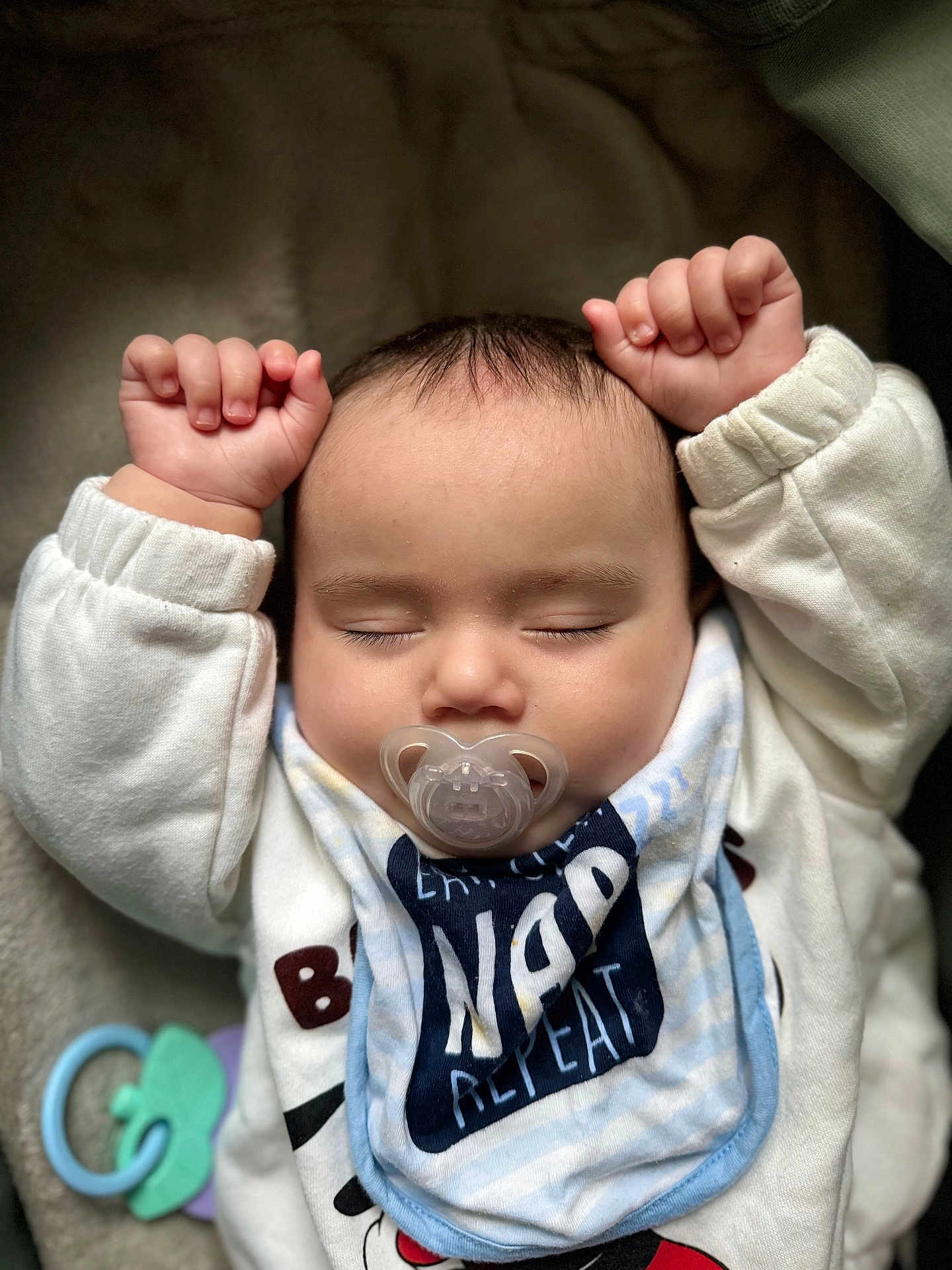 Huraira is registered to the contest to win money with this photo: baby, sleeping, pacifier, bib, arms_up, clothing, infant, soft_surface, toy, closeup, cute, peaceful, child, indoors, portrait, head, face, small_hands, resting, napping