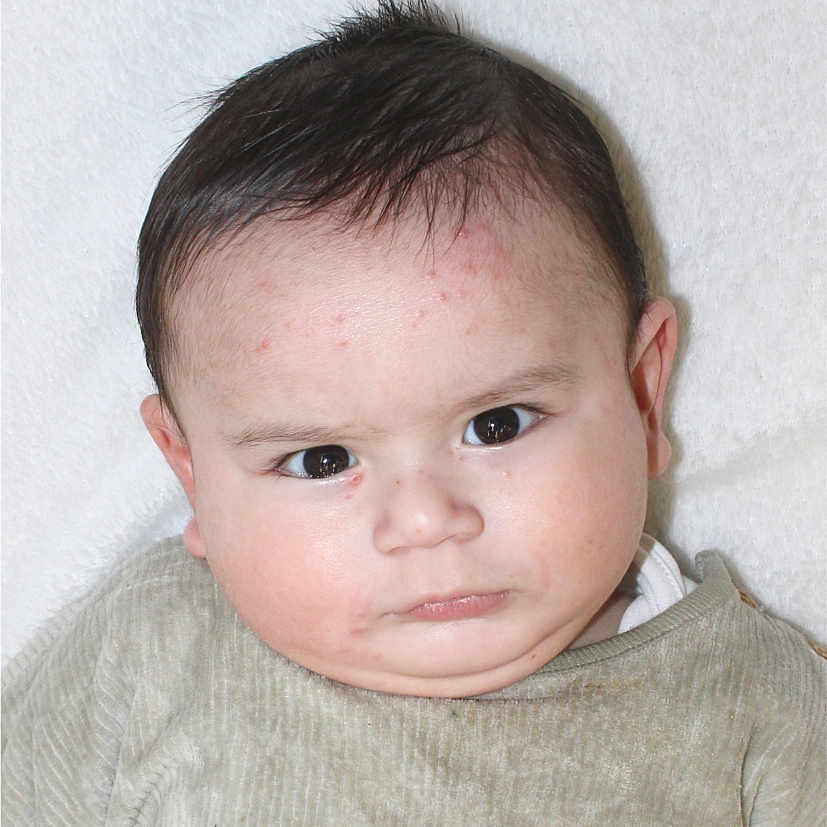 Huraira joined the competition — help win amazing prizes! baby, beige, chubby_cheeks, closeup, clothing, expression, eyes, face, furrowed_brow, hair, head, indoors, infant, lying_down, person, portrait, serious, skin, soft_texture, white_background