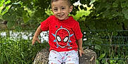 Akim a rejoint le concours — aidez-le/la à gagner de superbes lots ! boy, casual_clothing, child, cute, daylight, grass, greenery, happy, leaves, nature, outdoor, park, person, portrait, red_tshirt, shorts, smile, sneakers, spiderman, tree_stump