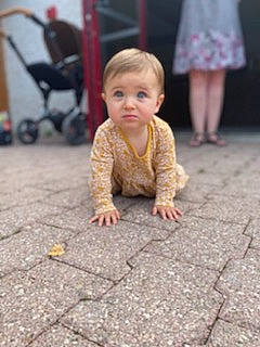 Romy a rejoint le concours — aidez-le/la à gagner de superbes lots ! asphalt, baby, baby_toddler_clothing, crawling, floor, flooring, foot, fun, grass, happy, hardwood, human_body, human_leg, leg, person, road, road_surface, sidewalk, sitting, toddler