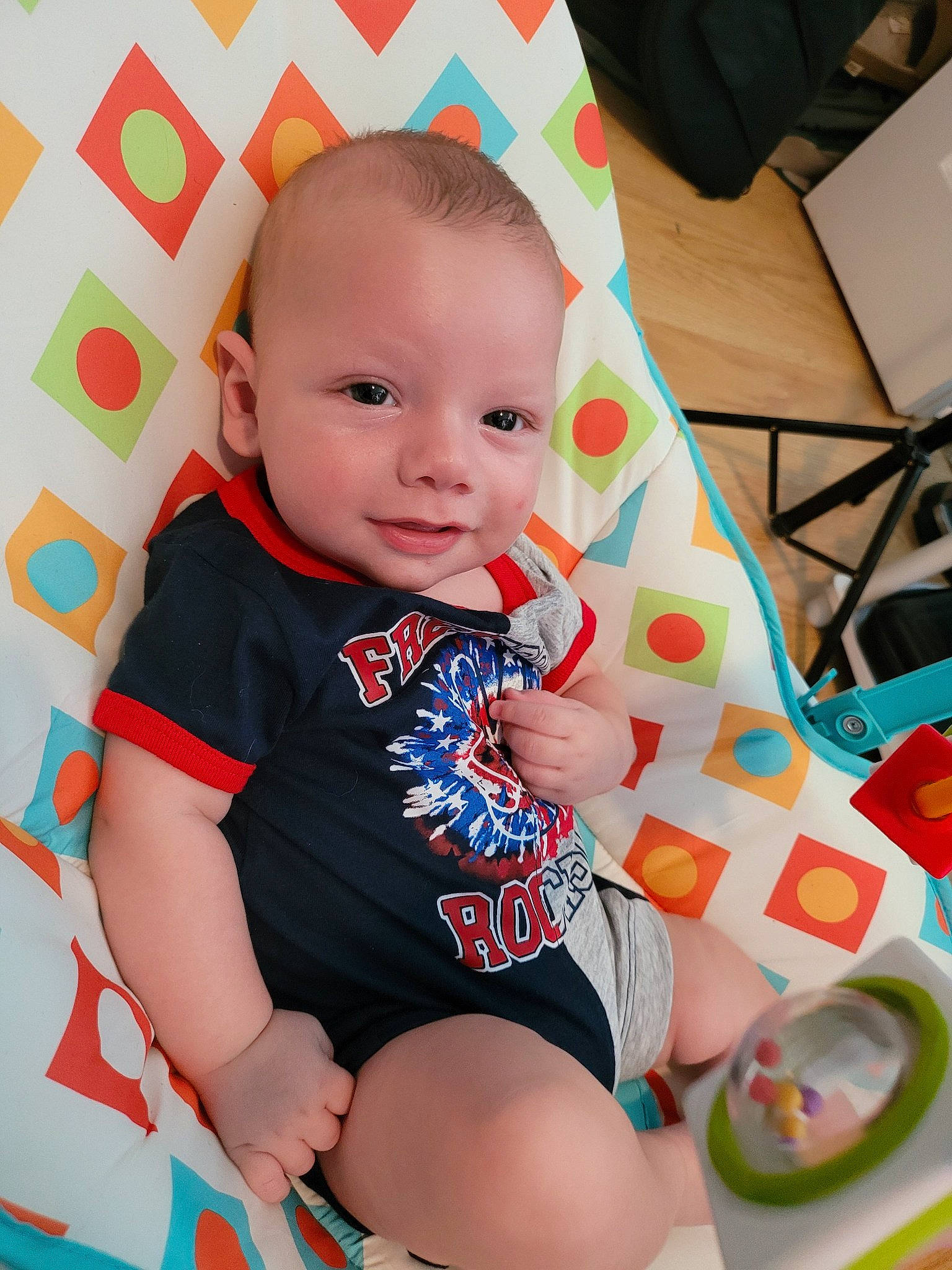 Killian is registered to the contest to win money with this photo: arm, baby, baby_toddler_clothing, cheek, child, eye, fun, happy, human_leg, iris, knee, orange, pattern, person, shirt, skin, sleeve, smile, t_shirt, thigh