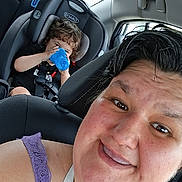 Damion is registered to the contest to win money with this photo: adult, car, car_seat, casual, child, clothing, drinking, face, hair, happy, interior, person, purple_top, safety, seatbelt, selfie, sippy_cup, smile, transportation, window