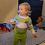 animated_show, blurred_motion, buzz_lightyear_costume, cabinet, car, carpet, child, clothing, floor, foot, furniture, hair, indoor, living_room, person, plastic_toy, television, toddler, toy, toy_car