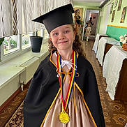 Sofia participe au concours pour gagner de l'argent avec cette photo : child, girl, graduation, cap, medal, cape, smile, hallway, curtains, dress, floor, portrait, celebration, indoor, flowers, carpet, person, award, happy, event