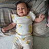 baby, child, infant, bed, pillow, striped_pillow, white_clothing, yellow_flowers, smiling, lying_down, cute, relaxed, indoor, person, soft_fabric, home, sleepwear, toddler, portrait, young