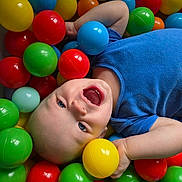 Emilio is registered to the contest to win money with this photo: toddler, child, ball_pit, colorful_balls, blue_shirt, happy, laughing, play, indoor, plastic_balls, young_child, smiling, fun, cute, face, head, skin, blue_eyes, casual_clothing, joy